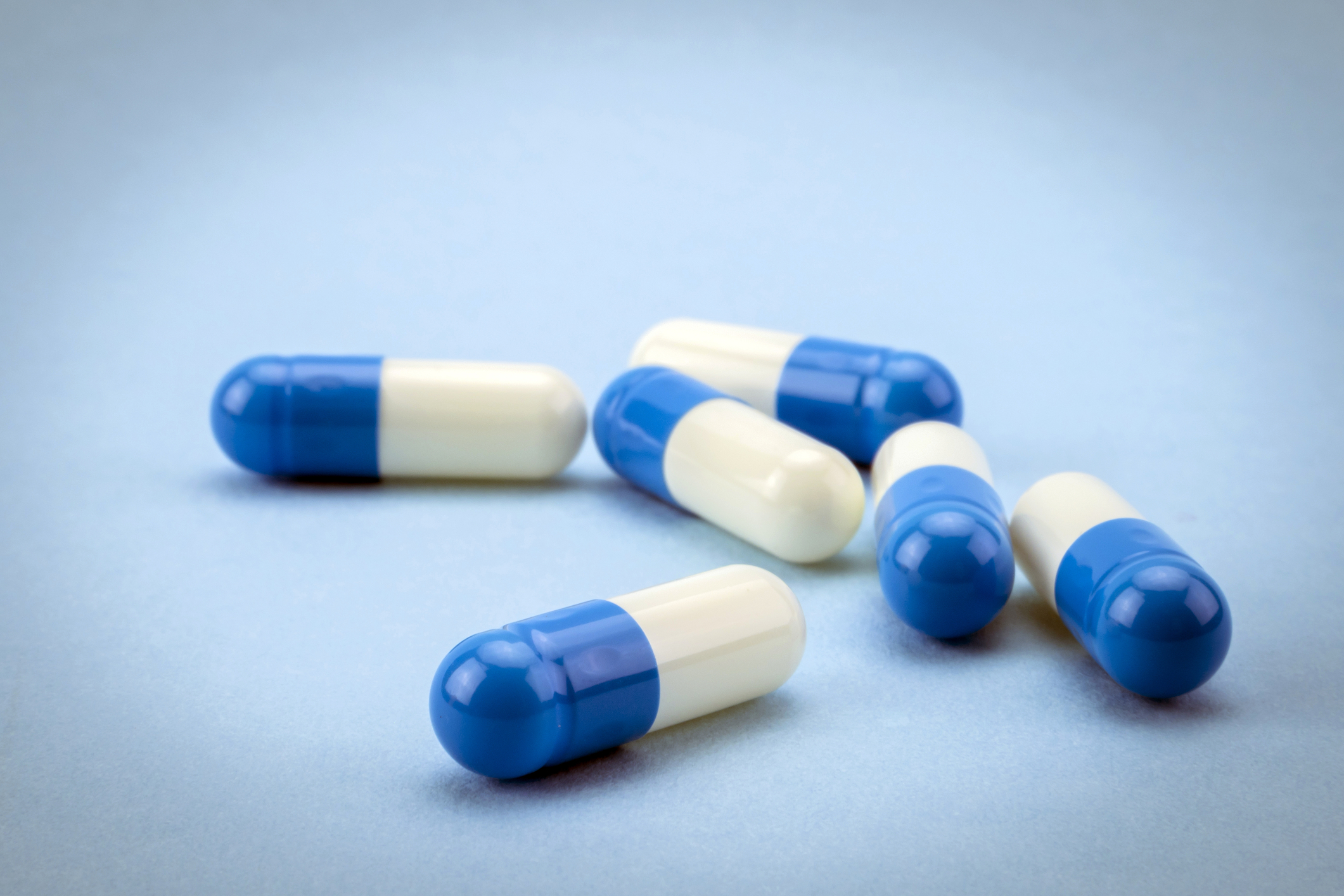 Pílulas azuis e brancas em um fundo azul