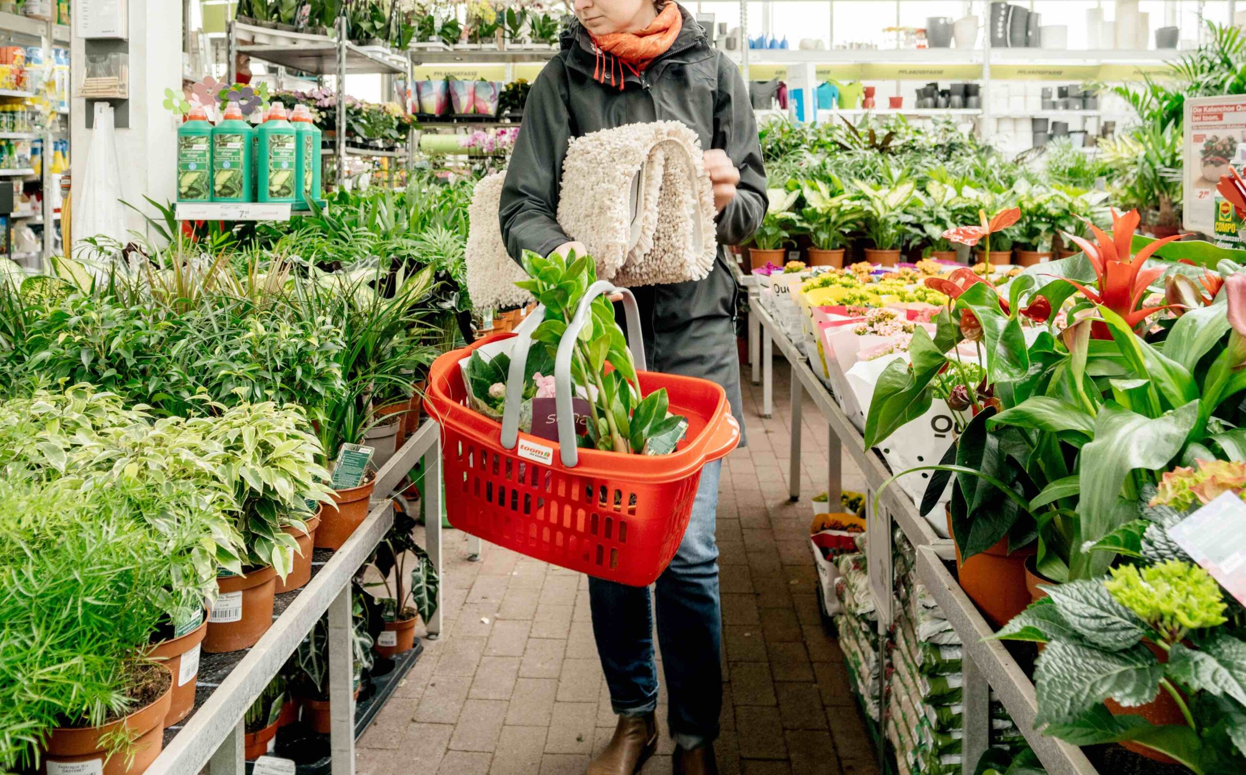 Uma mulher com um cesto de compras no corredor de produtos de uma mercearia.