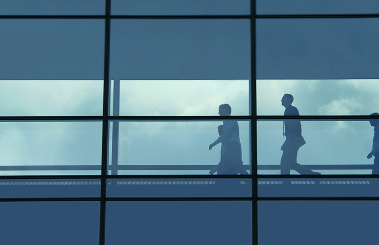 People walking on an elevated walkway between buildings.