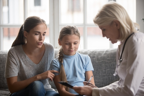 A medical professional speaking with a mom and daughter.
