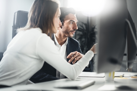 Colegas de trabalho a olhar para um ecrã de computador.