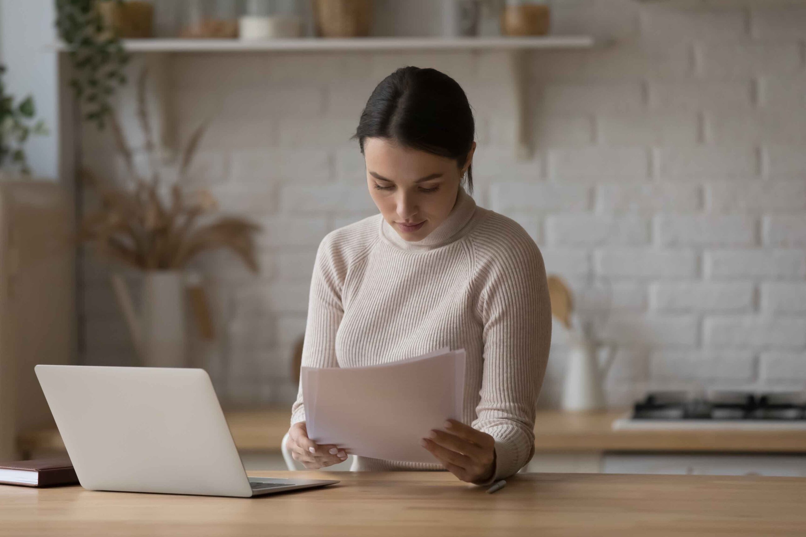 Une femme lisant des documents dans sa cuisine.