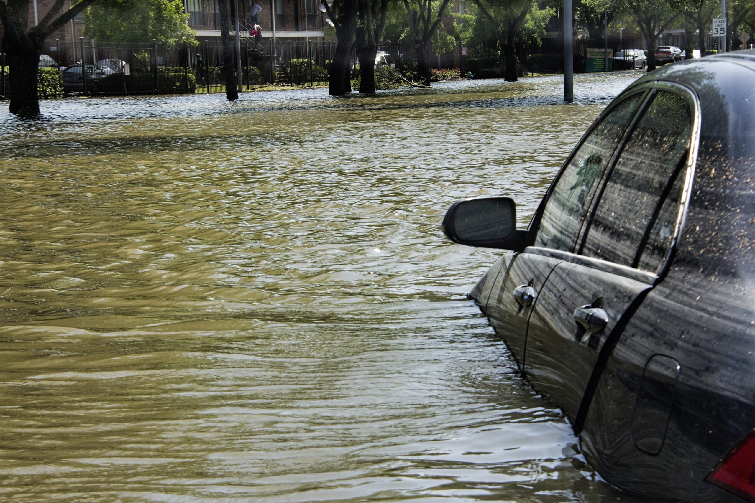 A vehicle halfway submerged on a flooded street.