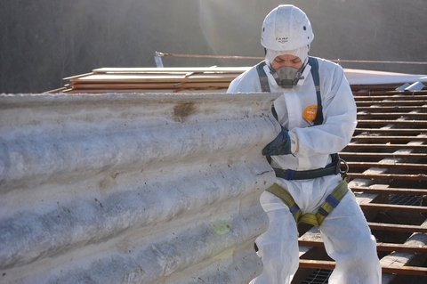 A worker in a hazmat suit pushing a large item.