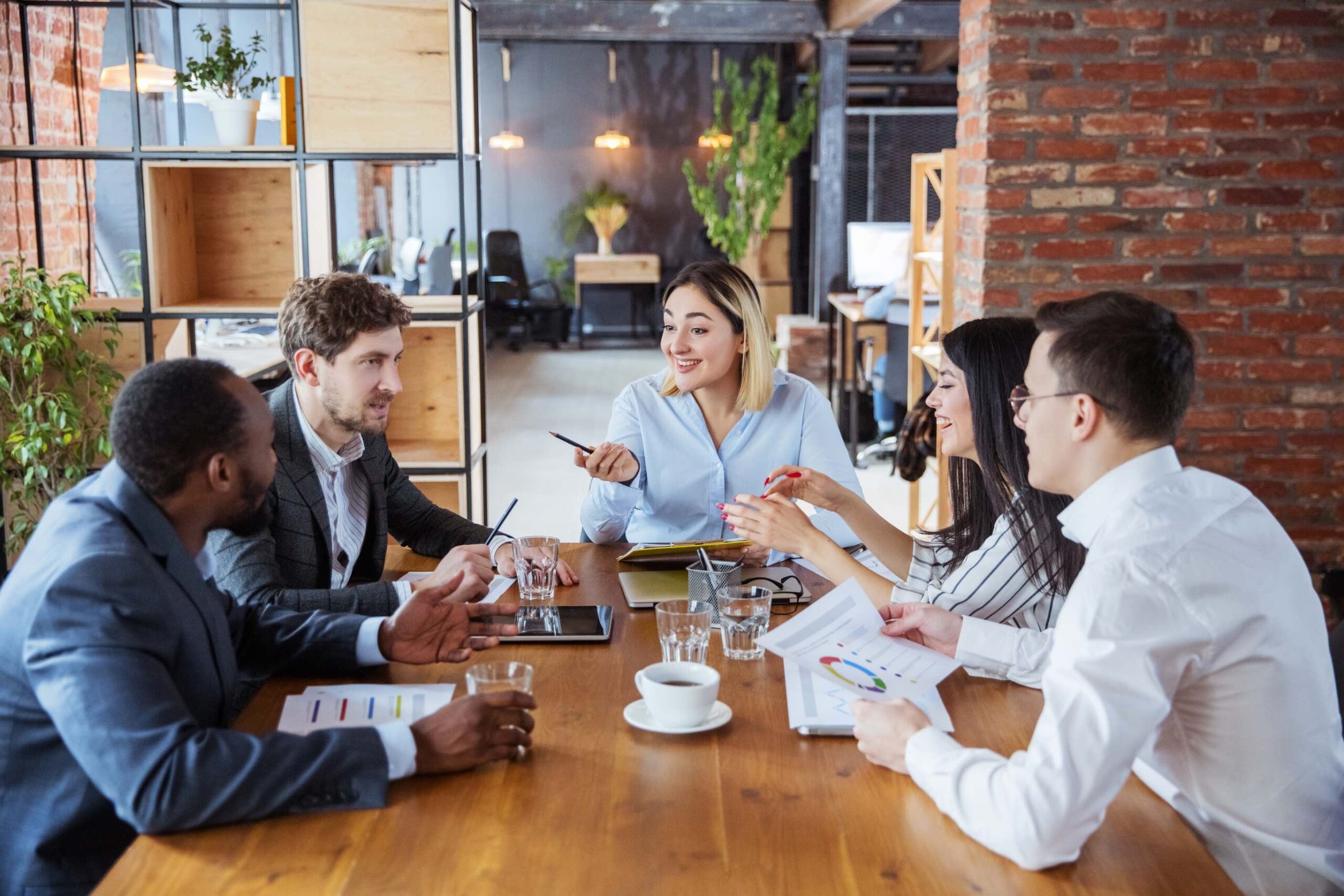 Five employees laughing around a conference table.