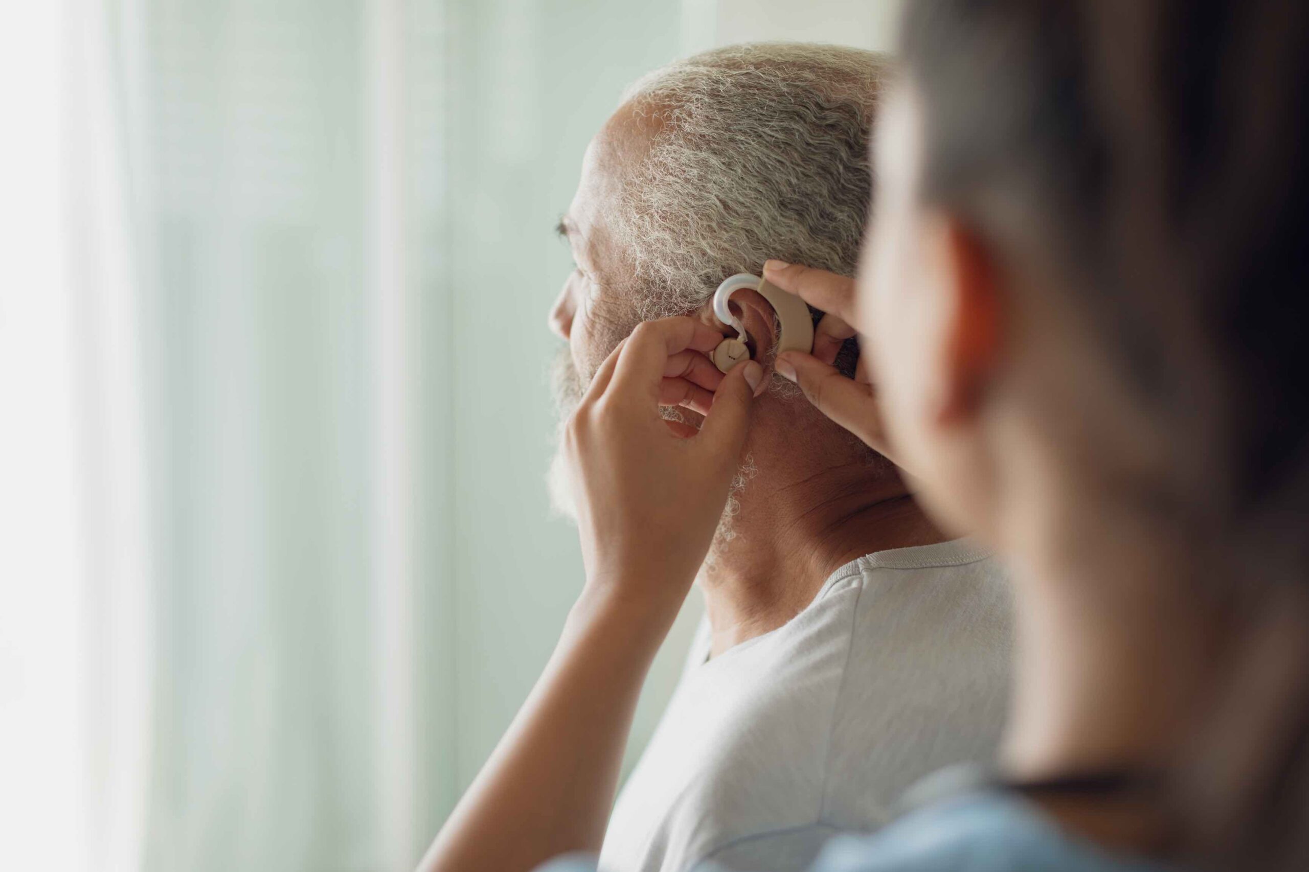 An elderly man being fitted with a hearing aide.