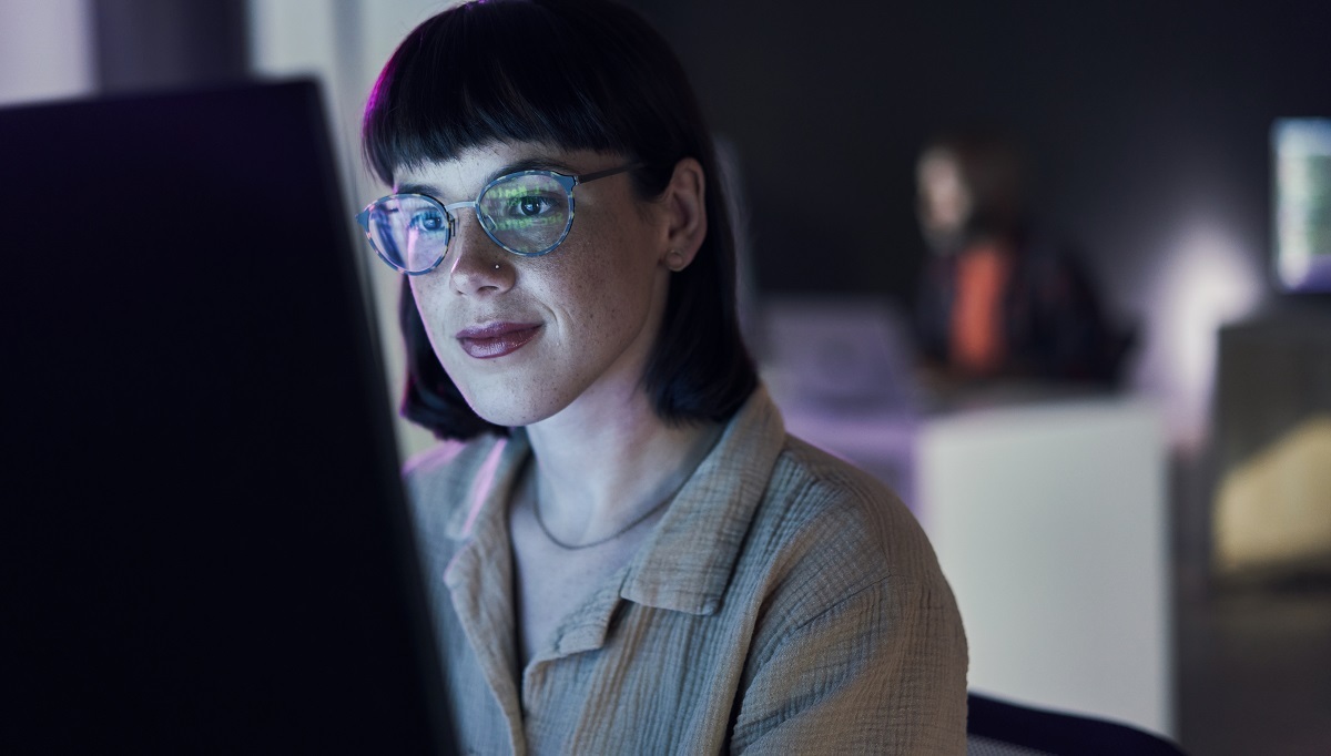 Das Leuchten eines Computerbildschirms auf dem Gesicht einer Frau.