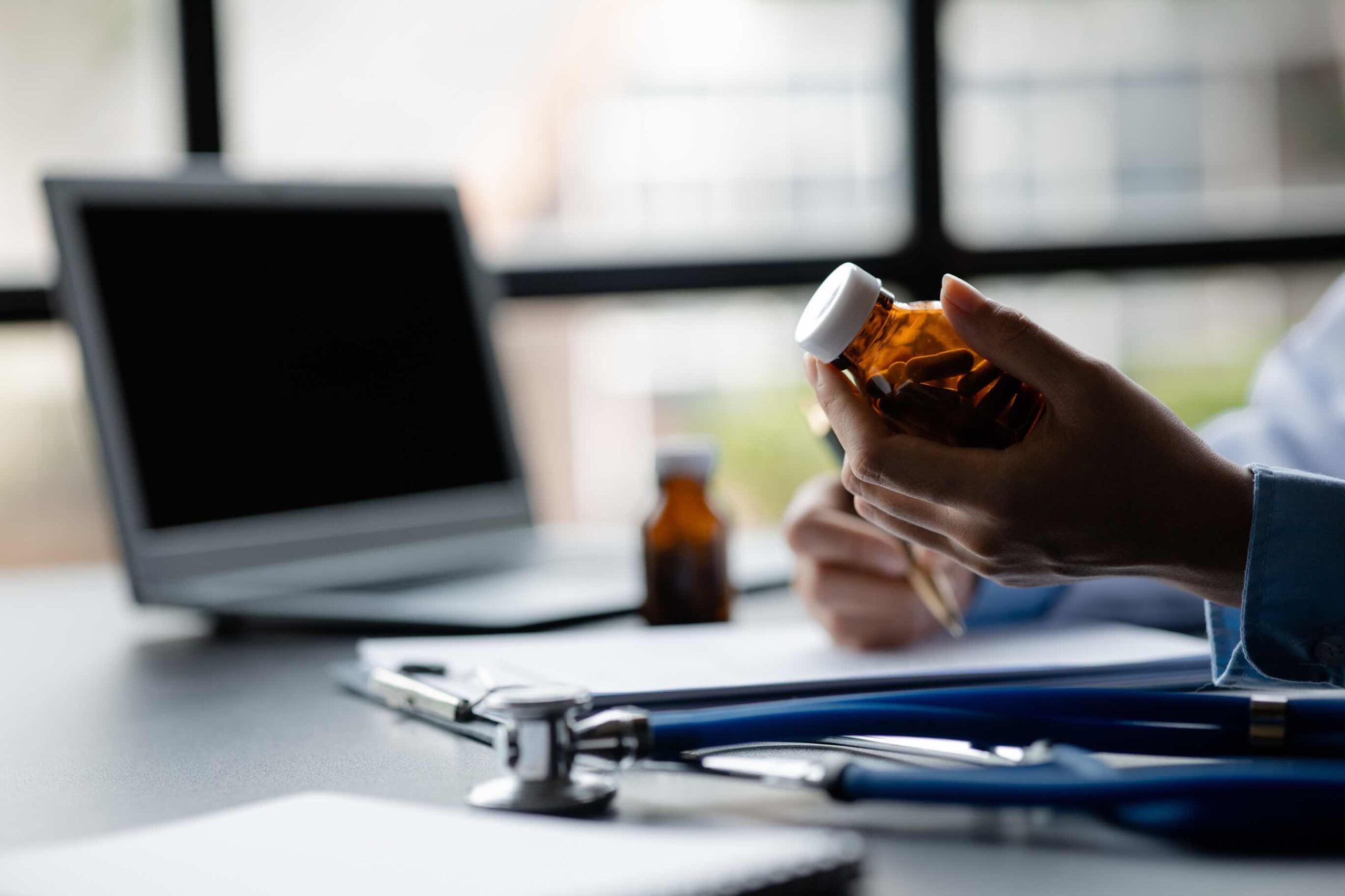 Uma mão segurando um frasco de comprimidos com prescrição médica.