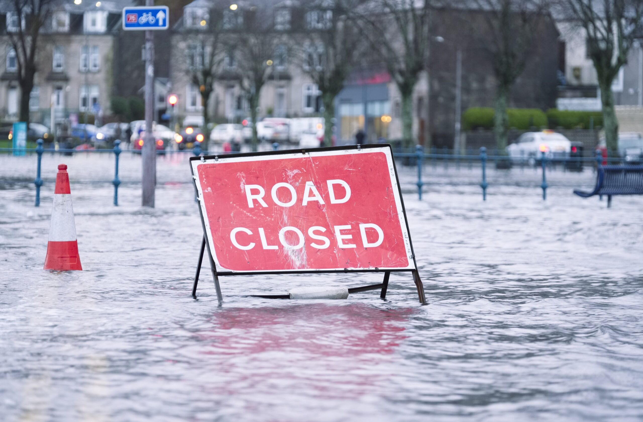 Um sinal de &quot;Estrada Fechada&quot; no meio de uma rua inundada.