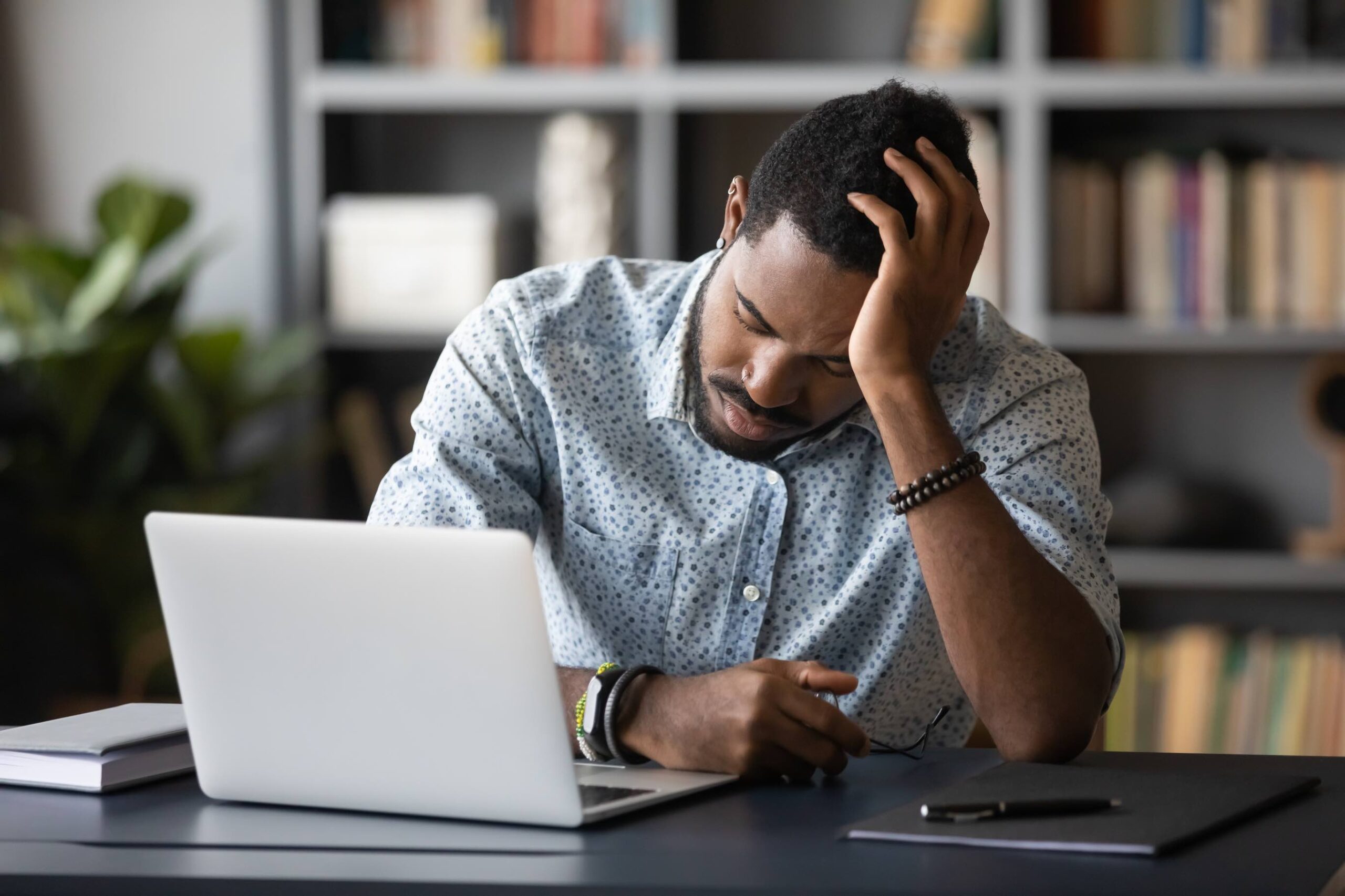 Un homme abattu assis à un bureau, la tête à la main.