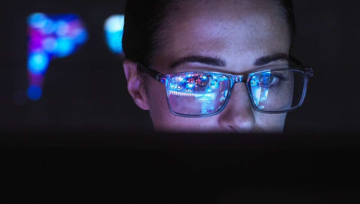 De reflectie van een computer op de bril van een vrouw.