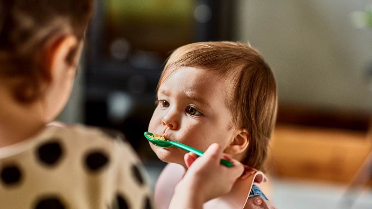 A mother feeds her child a spoonful of food.