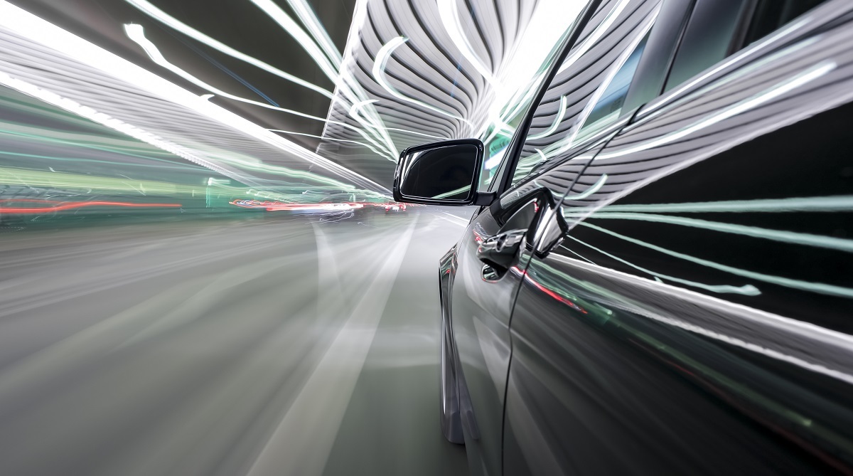 An automobile driving through a colorful tunnel.