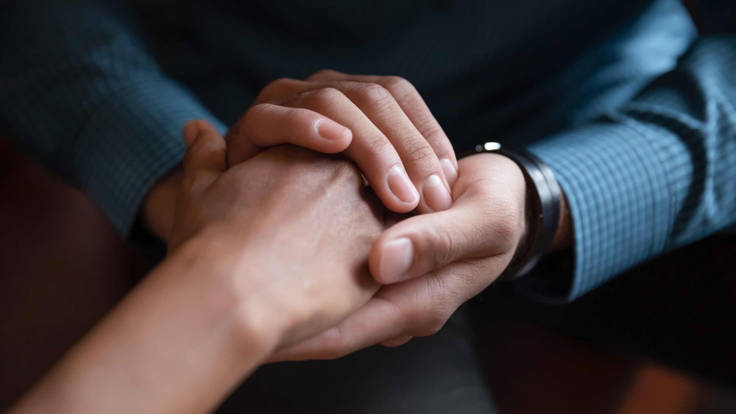 Een close-up van drie mensen die elkaars hand vasthouden.