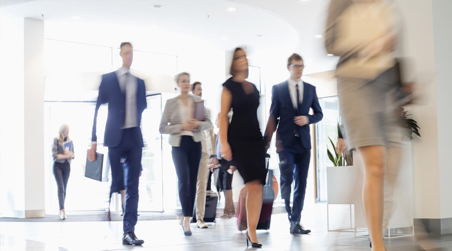 A crowd of professionals walking down a hallway.